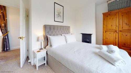 a bedroom with a white bed and a wooden cabinet at Bunkers Hill Cottage in Tackley