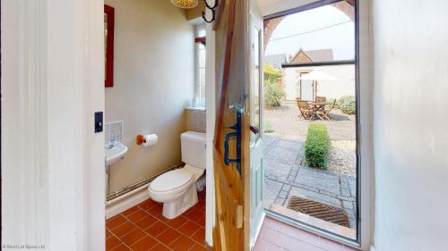 a bathroom with a toilet and a view of a patio at Bunkers Hill Cottage in Tackley