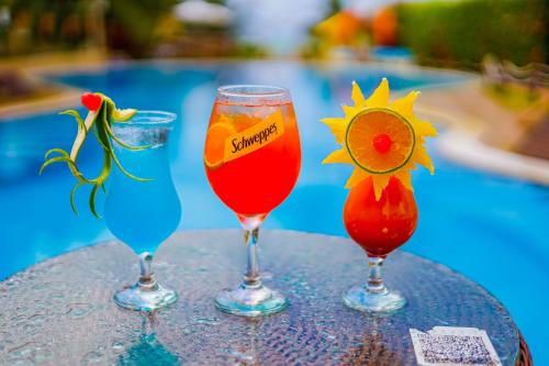three wine glasses sitting on a table next to a pool at Pousada Polymar in Maragogi
