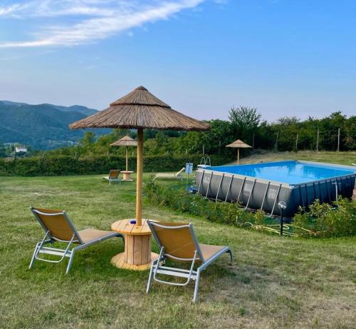 2 sillas y una mesa con sombrilla y piscina en Yurte in Langa, en Bosia