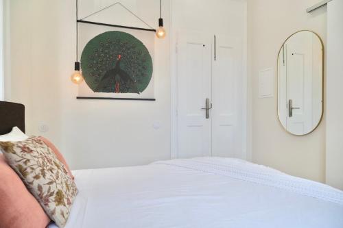 a white bedroom with a bed and a mirror at Vila Julieta Guesthouse in Coimbra