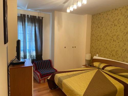 1 dormitorio con 1 cama, TV y silla en apartamentos beach langosteira 2 en Finisterre