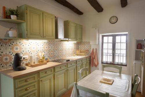 una cocina con armarios verdes, una mesa y una ventana en La Petite Maison du Périgord, en Tourtoirac