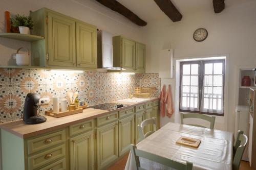 a kitchen with green cabinets and a table and a window at La Petite Maison du Périgord in Tourtoirac