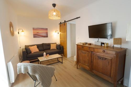 un salon avec un canapé et une télévision à écran plat dans l'établissement La Petite Maison du Périgord, à Tourtoirac