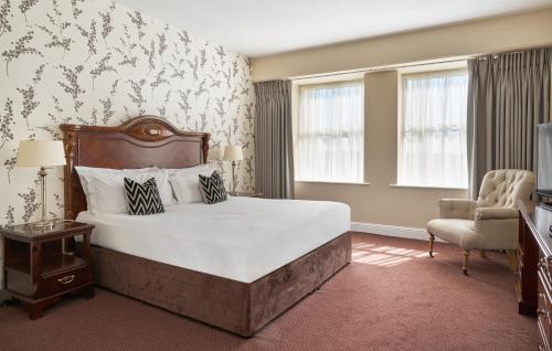 a bedroom with a large bed and a chair at Summerhill House Hotel in Enniskerry