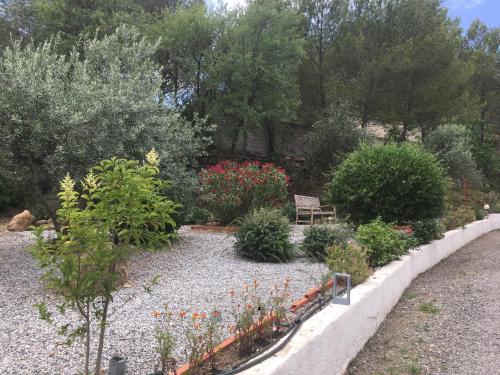 a garden with a bench and some flowers and trees at La Villa du Menhir Gîte in Bize-Minervois