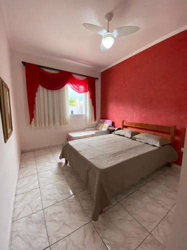 um quarto com uma cama e uma parede vermelha em Casa dos Andrade em Caraguatatuba em Caraguatatuba