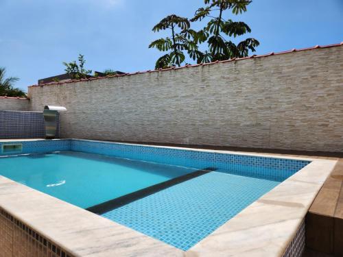 - une piscine dans un mur de briques avec une piscine dans l'établissement Casa dos Andrade em Caraguatatuba, à Caraguatatuba