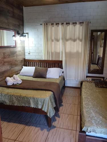 a bedroom with two beds and a mirror at Hotel Praia Do Rosa in Praia do Rosa