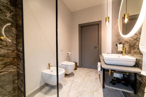 a bathroom with a sink and a toilet and a mirror at Hotel Gothards in Kuldīga