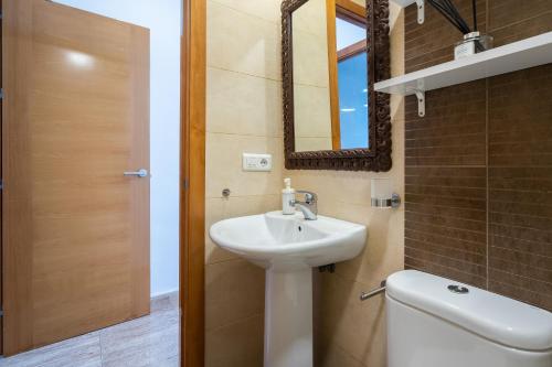 ein Badezimmer mit einem Waschbecken, einem WC und einem Spiegel in der Unterkunft Ático Plata in Cádiz