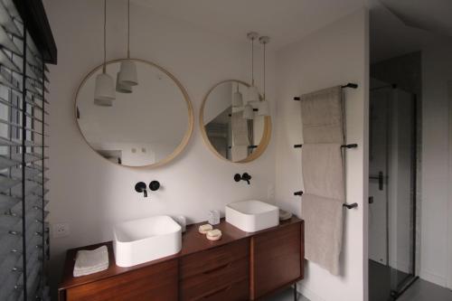 La salle de bains est pourvue de 2 lavabos et de 2 miroirs sur le mur. dans l'établissement Les pieds dans l o a Port navalo, à Arzon