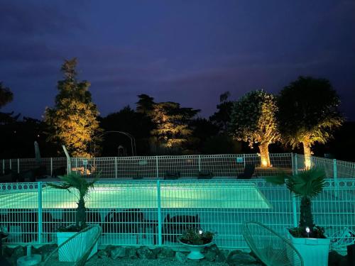 - une piscine avec des palmiers et des lumières la nuit dans l'établissement LA PROMENADE, à Coings
