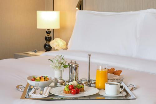 a breakfast tray with fruit and juice on a bed at Jumeirah Jabal Omar Makkah in Makkah