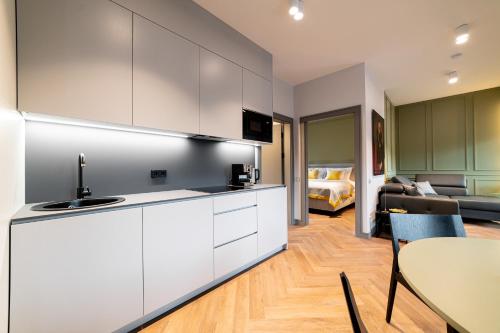 a kitchen with white cabinets and a living room at Hotel Gothards in Kuldīga