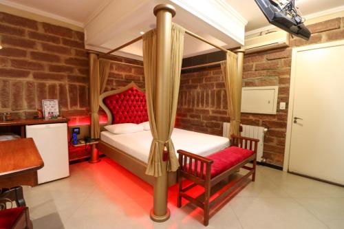 a bedroom with a four poster bed and two chairs at Motel Casa de Pedra in Caràzinho