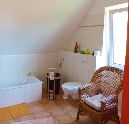 a bathroom with a toilet and a bath tub and a chair at Loft Sierksdorf in Sierksdorf