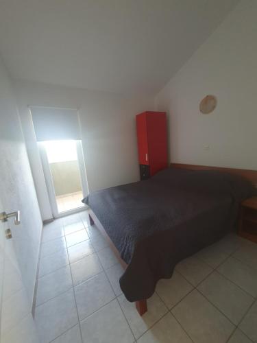 a bedroom with a bed and a red cabinet at Apartments Jelinic in Polača