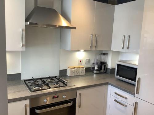 a kitchen with white cabinets and a stove and a microwave at Entire 2 bedroom house in Tamworth in Tamworth