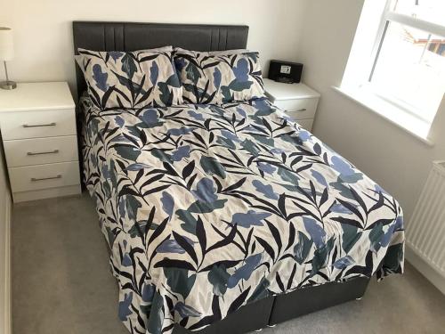 Schlafzimmer mit einem Bett mit einer blauen und weißen Bettdecke in der Unterkunft Entire 2 bedroom house in Tamworth in Tamworth