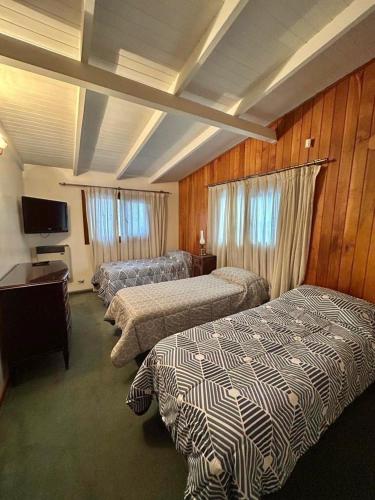 ein Hotelzimmer mit drei Betten und einem Fernseher in der Unterkunft La Noemi in Esquel