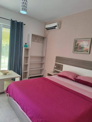 a bedroom with a large bed with a pink bedspread at Miro guesthouse in Tivat