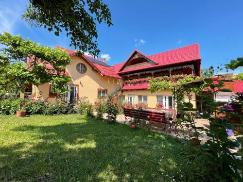 a house with a red roof and a bench in the yard at Pensiunea Alina in Agapia