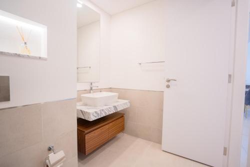 a white bathroom with a sink and a mirror at Nasma Luxury Stays - Fancy Apartment With Balcony Close To MJL's Souk in Dubai