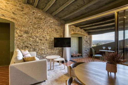 a living room with a table and a stone wall at Mas Cusi in Palau-Saverdera