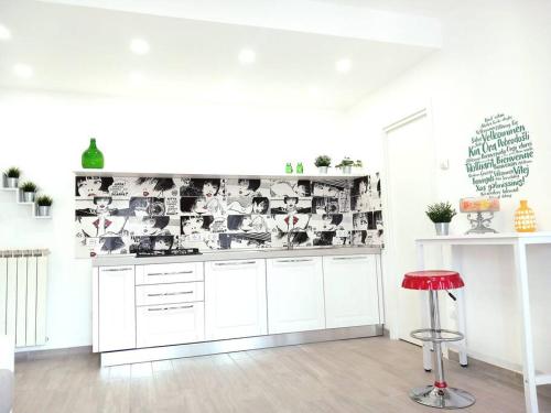 a kitchen with white cabinets and a red stool at Casa Vacanze MARE BOOM in Martinsicuro