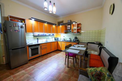 a kitchen with orange cabinets and a table and a refrigerator at Guesthouse Old Town in Kutaisi