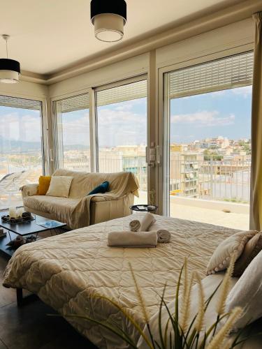 a bedroom with a bed and a couch and windows at Kapsalakis Penthouse in Korinthos