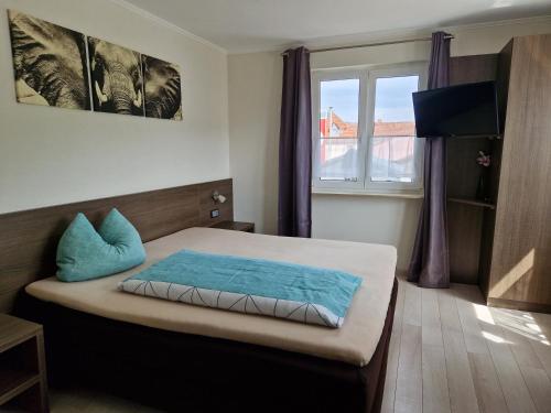 ein Schlafzimmer mit einem Bett mit blauen Kissen und einem Fenster in der Unterkunft LandGASTHOF Rose in Dammbach