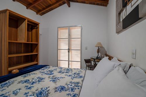 um quarto com uma cama, uma mesa e uma janela em Hotel Chalés Cachoeira 3 Quedas em Brotas