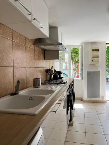 - une cuisine avec un grand évier et une cuisinière dans l'établissement Maison Emile - Coeur du village - 8 personnes - Clim - Superbe literie, à Leucate