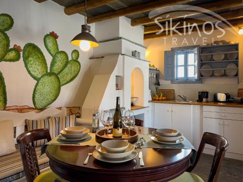 uma cozinha e sala de jantar com uma mesa e uma parede de cactos em Traditional Maisonette with picturesque Chora View em Chora Folegandros