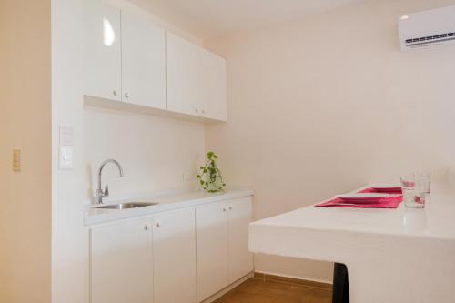 a white kitchen with white cabinets and a sink at Suites Turquesa in Cozumel