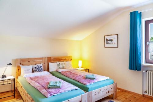 two beds in a bedroom with blue curtains at Ferienwohnung Bergblick in Unterammergau