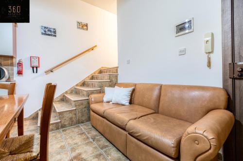 een bruine leren bank in een woonkamer met een trap bij Lovely, comfy 2BR home with comfy sofa w/WIFI & AC by 360 Estates in St Paul's Bay