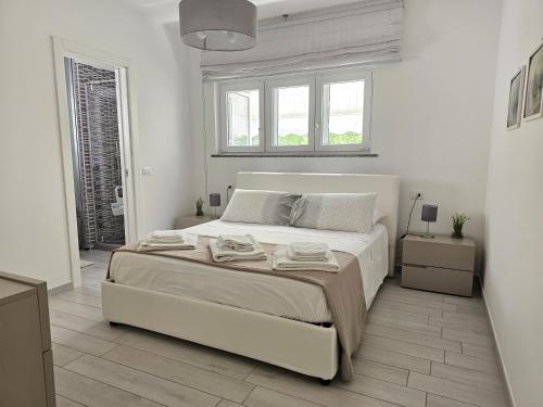 Un dormitorio blanco con una gran cama blanca y ventanas. en Casa Elia - Puglia Mia Apartments, en Monopoli