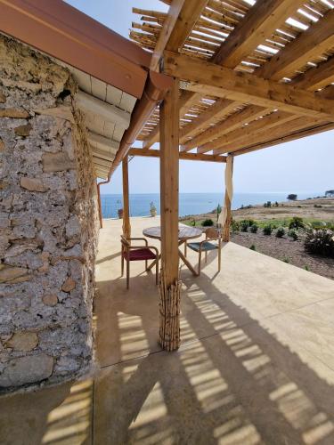 a wooden pergola with a table and bench on a patio at Tendu' Punta Bianca Glamping Camp in Palma di Montechiaro