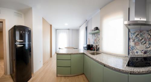 a kitchen with green cabinets and a black refrigerator at Apartamentos Villa Zoila Nigrán in Nigrán
