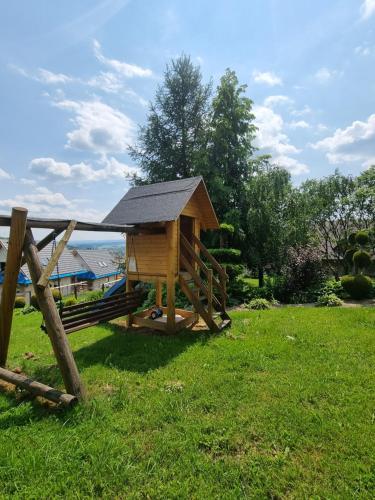 a wooden dog house with a roof on the grass at Willa Anna Kluszkowce in Kluszkowce
