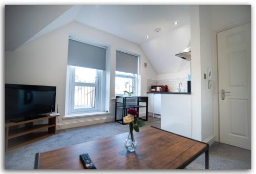 a living room with a vase of flowers on a table at Adorable Flat in Maidstone - Sleeps 3 in Kent