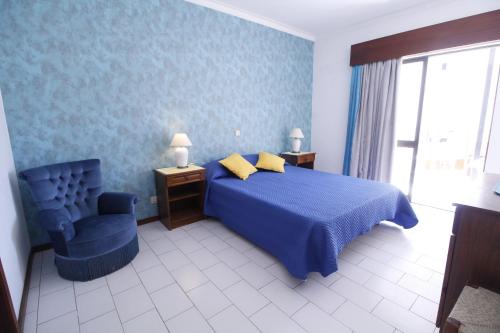 ein Schlafzimmer mit einem blauen Bett und einem blauen Stuhl in der Unterkunft ApartamentoSolPraia - Cruzeiro in Portimão
