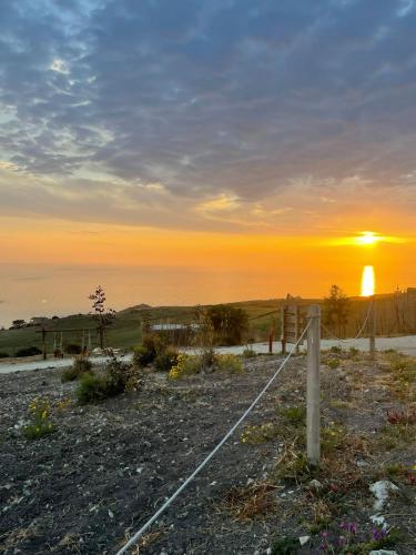 a sunset over the ocean with a fence at Tendu' Punta Bianca Glamping Camp in Palma di Montechiaro