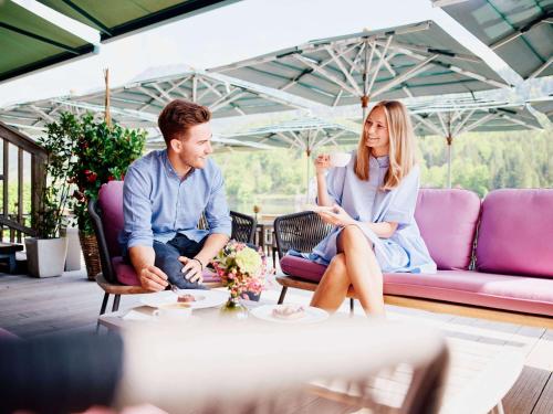 a man and a woman sitting on a couch at TAUROA Seehotel Grundlsee in Grundlsee