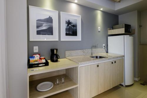 a kitchen with a counter with a sink and a refrigerator at Promenade Link Stay Barra da Tijuca in Rio de Janeiro