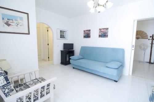 ein Wohnzimmer mit einem blauen Sofa und einem TV in der Unterkunft ApartamentoSolPraia - Cruzeiro in Portimão